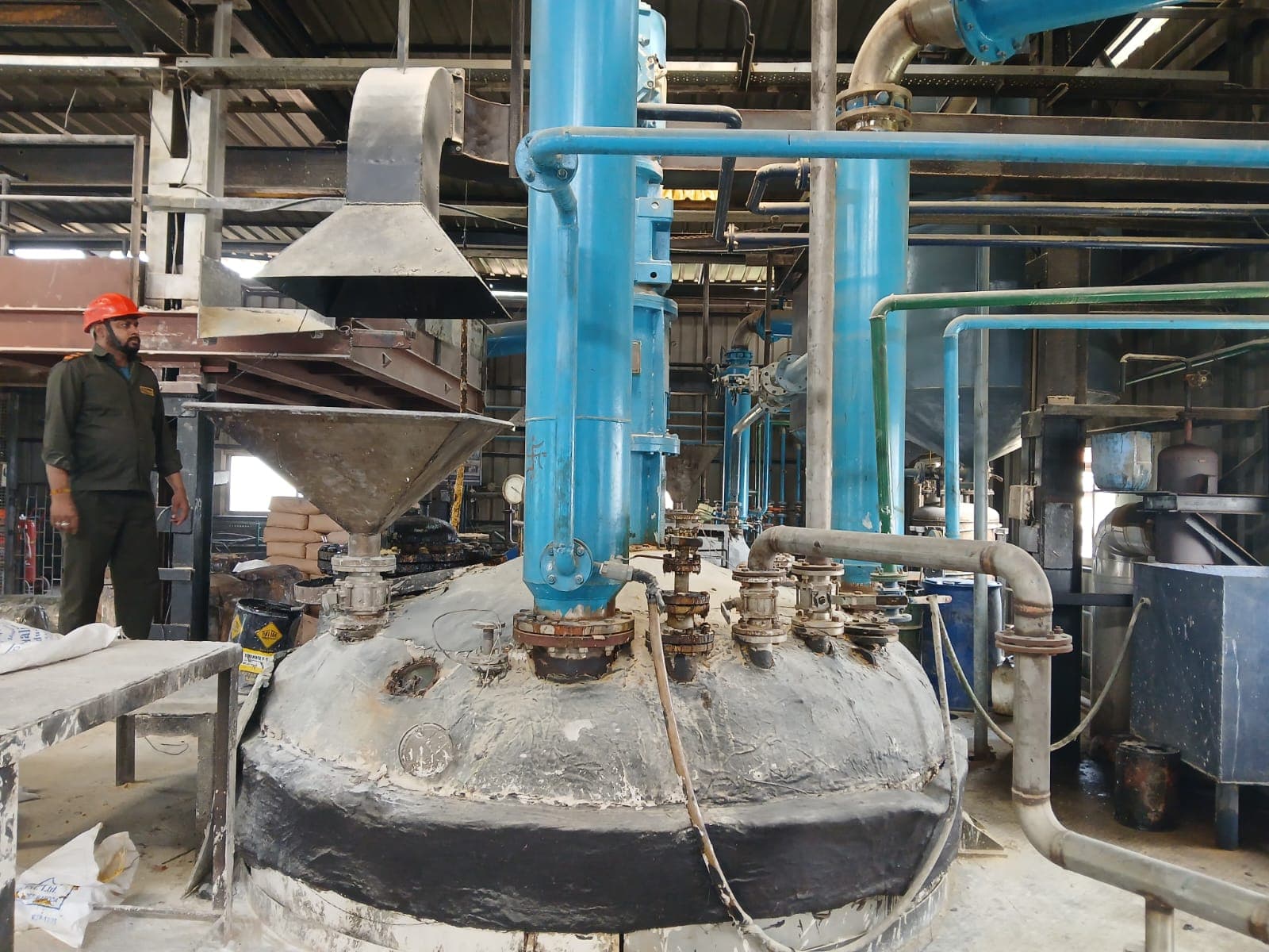 An operator working at a reactor vessel in the oil processing plant